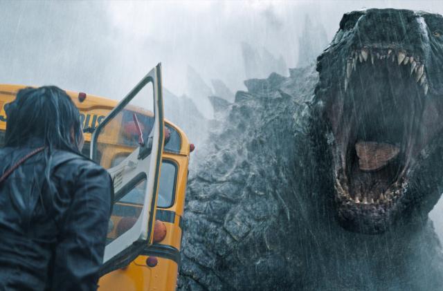 Godzilla roars at a person standing next to a school bus in Apple TV+ series Monarch: Legacy of Monsters.