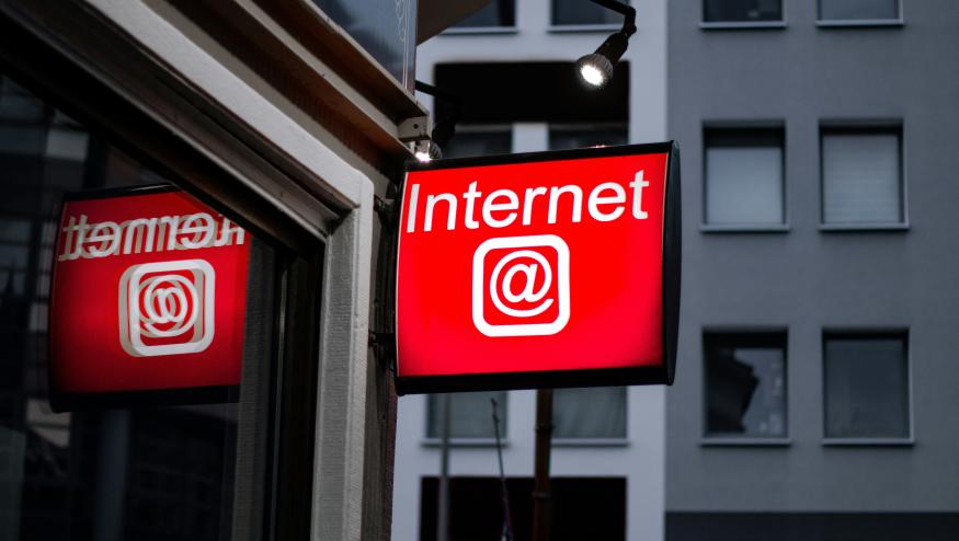 A red sign hanging outside a building. It reads "Internet" and includes an "at" symbol.