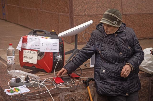 KHERSON, UKRAINE - NOVEMBER 17: A resident waits for her phone to charge at a temporary charging point and internet hotspot via a Starlink device on November 17, 2022 in Kherson, Ukraine. Ukrainian forces took control of Kherson last week, as well as swaths of its surrounding region, after Russia pulled its forces back to the other side of the Dnipro river. Kherson was the only regional capital to be captured by Russia following its invasion on February 24. 