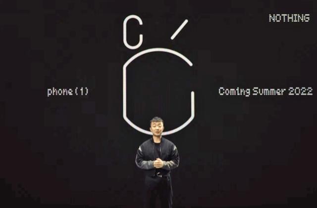 OnePlus founder Carl Pei stands in front of basic black/white text announcing the Nothing Phone (1) coming in summer of 2022.