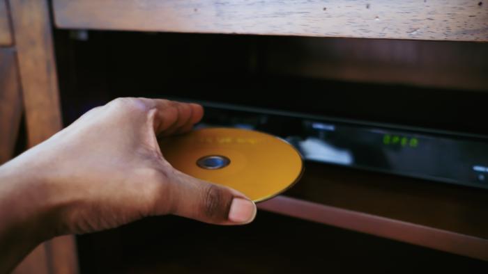 Close-up of unrecognizable black woman inserting disk into DVD player