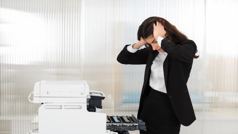 Irritated young businesswoman looking at printer machine at office