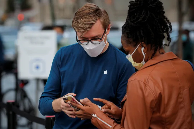 A customers speaks to an employee outside an Apple Store to pick up Apple's new 5G iPhone 12, as the coronavirus disease (COVID-19) outbreak continues in Brooklyn, New York, U.S. October 23, 2020.  REUTERS/Brendan McDermid