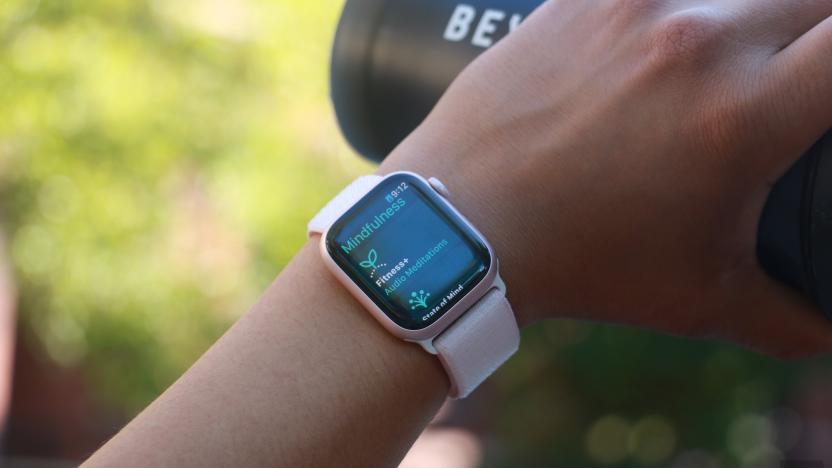 The Apple Watch Series 9 on a person's wrist, with the hand holding a black water bottle in the background. The screen shows the Mindfulness app.