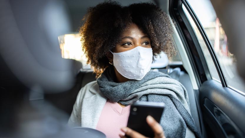 Mixed race woman with protective face mask travel by taxi. Businesswoman traveling by taxi during COVID-19 pandemic.