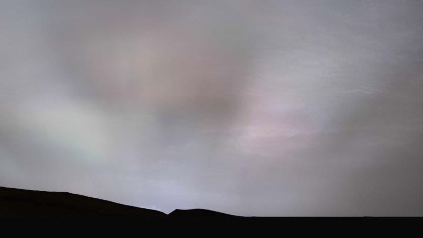 A photo of Martian sunbeams meeting a cloudy sky seen at the top of a mountain or hill in silhouette taken by NASA's Curiosity rover. 