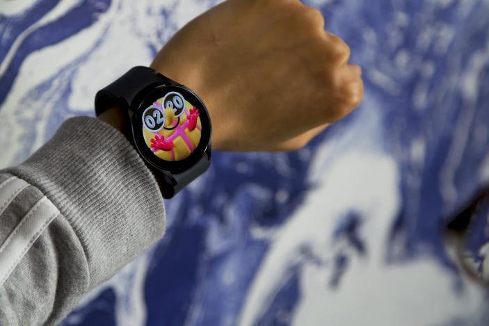 A person’s left wrist wearing the Samsung Galaxy Watch. Blue and white swirled background (blurred).