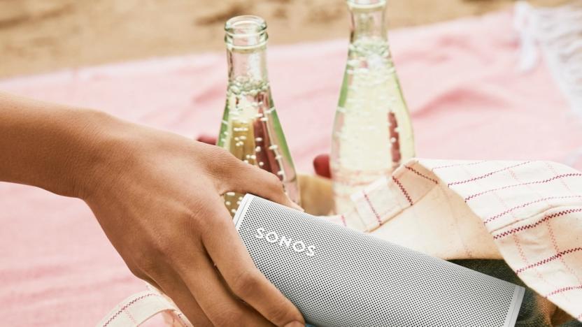 A closeup of a person's hand taking a Sonos Roam speaker out of a bag with bottles of a carbonated beverage behind it