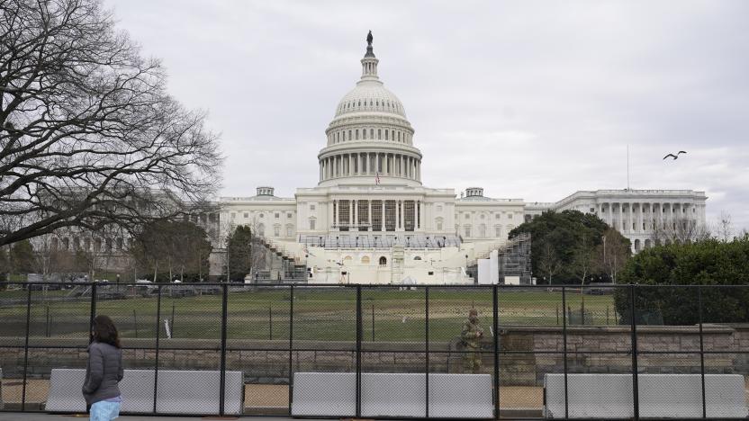 A woman walks past security fencing protecting the West Front of the U.S. Capitol in Washington, Friday, Jan. 8, 2021, as preparations take place for President-elect Joe Biden's inauguration after supporters of President Donald Trump stormed the building. (AP Photo/Patrick Semansky)
