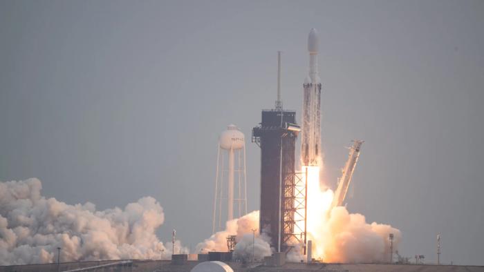 Photo of a SpaceX rocket, with the Psyche spacecraft attached to it, blasting off.