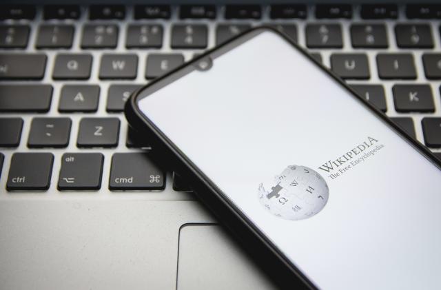 In this photo illustration a Wikipedia logo seen displayed on a smartphone screen with a computer keyword in the background in Athens, Greece on December 12, 2021. (Photo by Nikolas Kokovlis/NurPhoto via Getty Images)
