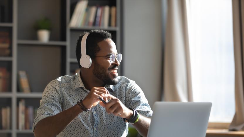 Happy relaxed millennial afro american business man wear wireless headphones look away rest at workplace finished work listening music podcast feel peace of mind concept sit at desk in sunny office