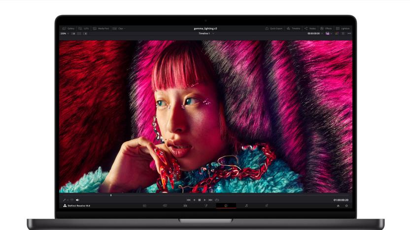 A press photo of the new Apple MacBook Pro powered by the new M3 chip. The dark gray laptop is facing forward with a photo of a young woman with brightly colored hair and a fuzzy blue top on the notebook's display.