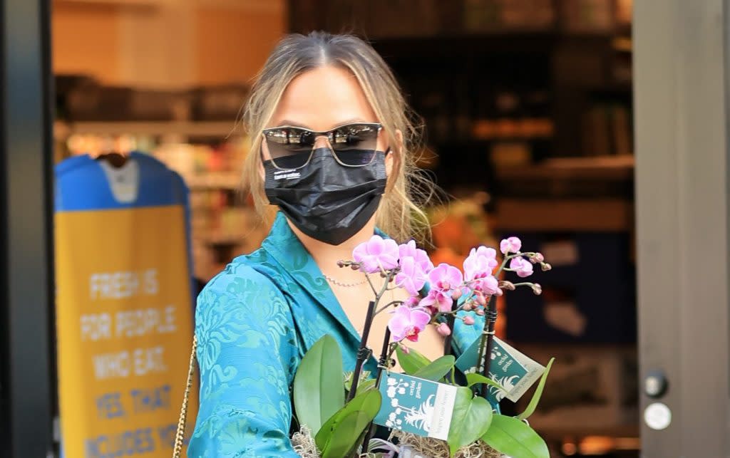 Chrissy Teigen fits the prettiest green high low dress with her go-to holiday sandals in St. Louis.  Barts