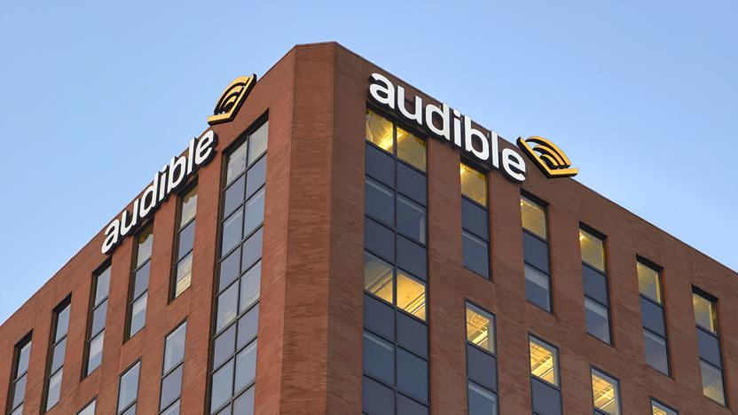 View from below of the top corner of Audible’s headquarters. The brown-red brick building has Audible logo signs on either side of the corner.