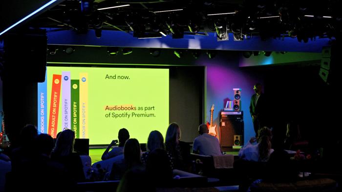 A dark stadium with a screen on stage announcing audiobooks as part of Spotify Premium.  