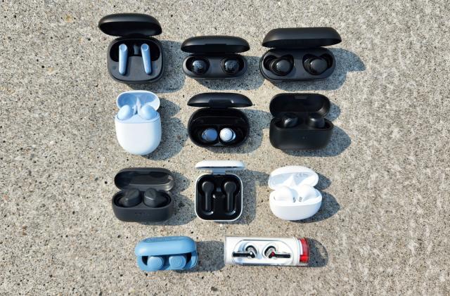 A selection of wireless earbuds sit organized in rows on a granite background.