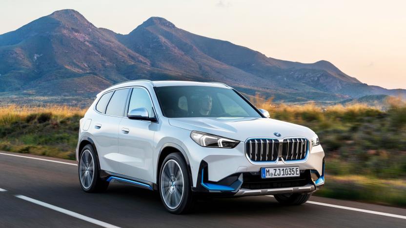 A white BMW iX1 xDrive30 SUV drives through a mid-western highway.