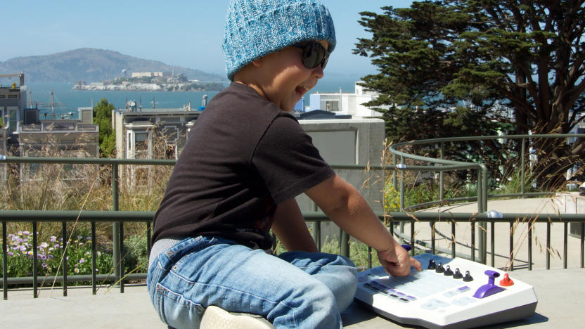 a small boy in a blue beanie playing with a myTRACK groovebox outside in San Francisco with Alcatraz in the background.