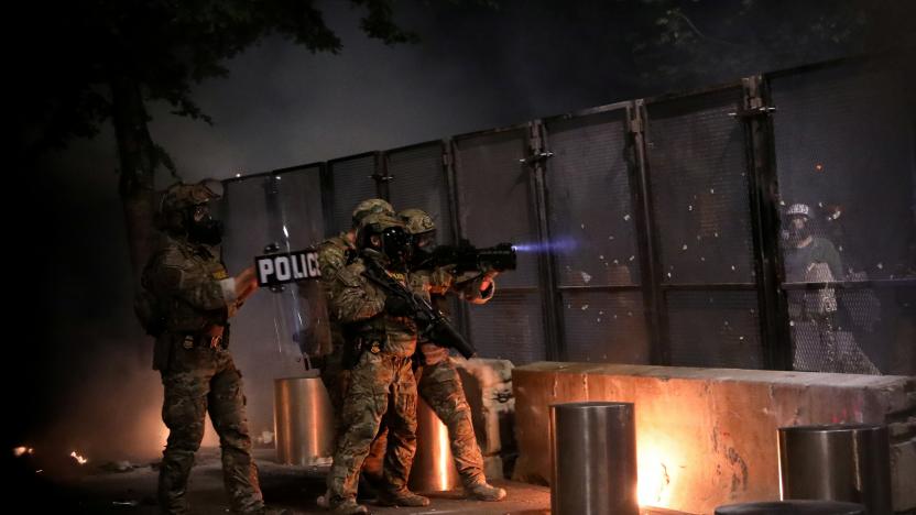 Federal law enforcement officials aim at protesters outside a fence during a demonstration against police violence and racial inequality in Portland, Oregon, U.S., July 24, 2020. REUTERS/Caitlin Ochs     TPX IMAGES OF THE DAY