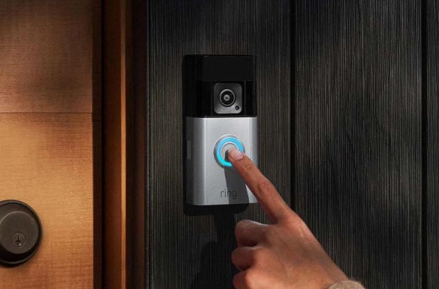 A hand pressing on a doorbell camera. 