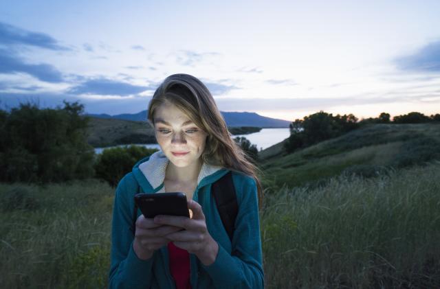 Teenage girl using her smart phone while hiking