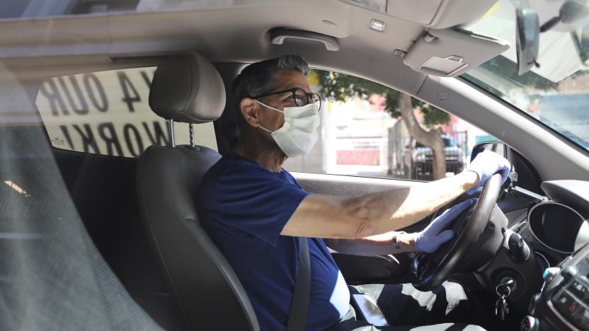 LOS ANGELES, CALIFORNIA - APRIL 16: A protestor wears a face mask and gloves as Uber and Lyft drivers with Rideshare Drivers United and the  Transport Workers Union of America conduct a ‘caravan protest’ outside the California Labor Commissioner’s office amidst the coronavirus pandemic on April 16, 2020 in Los Angeles, California. The drivers called for California to enforce the AB 5 law so that they may qualify for unemployment insurance as the spread of COVID-19 continues. Drivers also called for receiving back wages they say they are owed. (Photo by Mario Tama/Getty Images)