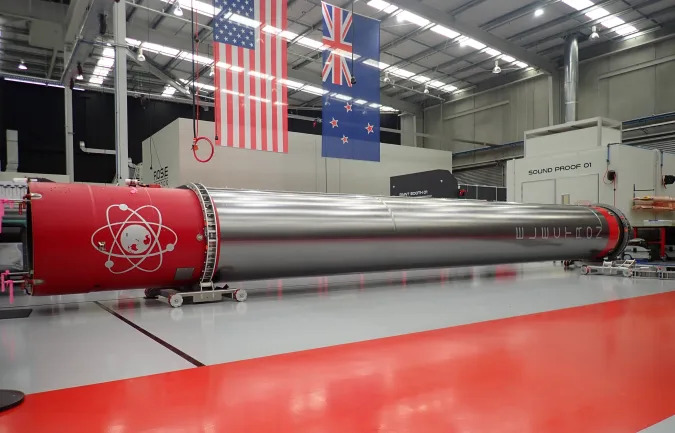 The Rocket Lab booster rocket seen in is storage hangar with a large red strip on the floor and red-capped ends on the rocket itself.