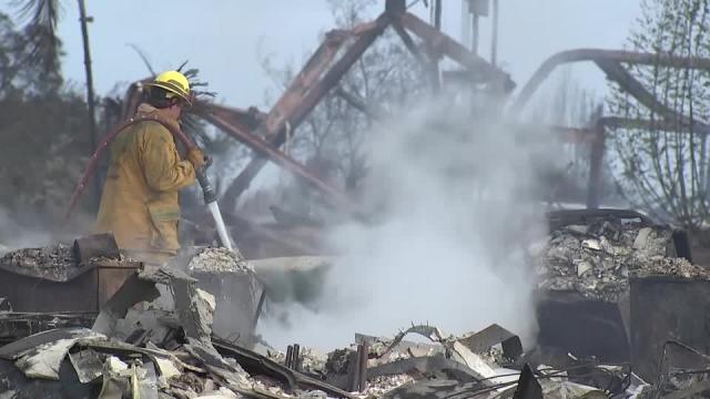 Firefighter standing in the rubble of a building destroyed by the Maui Wildfires.
