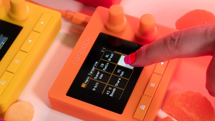 A manicured nail pushes down on the touchscreen of a Tangerine sampler. 