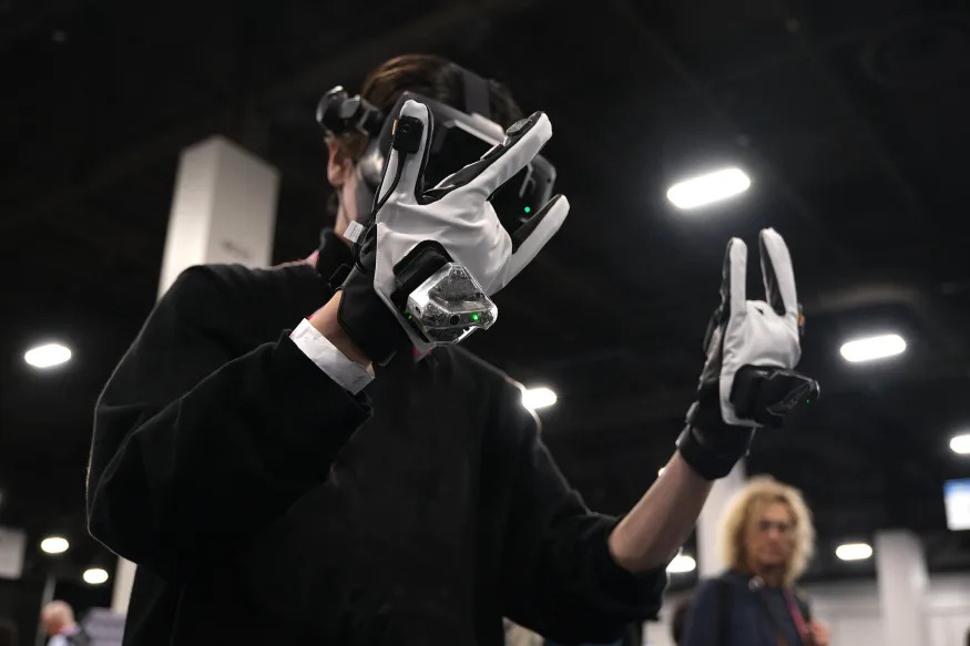 A man wearing a VR headset explores a virtual world with tactile glove accessories.