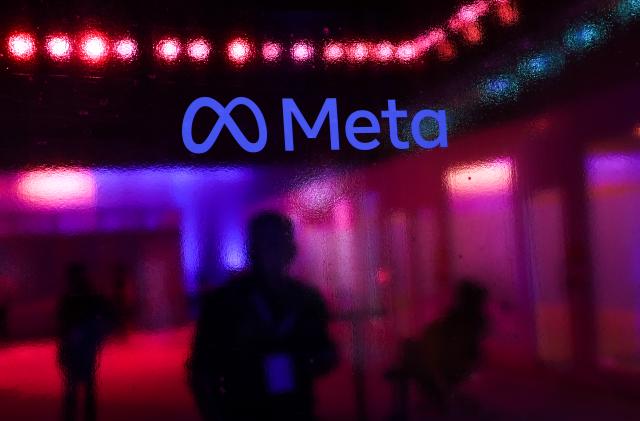 People walk behind a logo of Meta Platforms company, during an event in Mumbai, India, 20 September, 2023 (Photo by Niharika Kulkarni/NurPhoto via Getty Images)