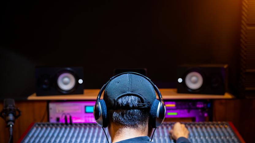 back of asian male professional music producer, sound engineer mixing a song on audio mixing console in recording studio. music production, post production concept