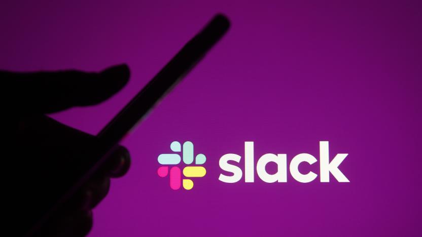 Silhouetted hand holding a phone while using Slack