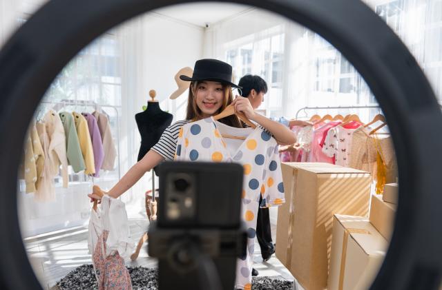 Fashion vlogger presenting dress to cellphone and showing clothes selling online live streaming