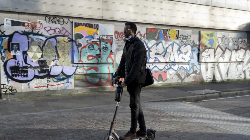 Warring a face covering on his chin, a commuter rides an eScooter past the graffiti on the exterior of a former office property in during the third lockdown of the Coronavirus pandemic, on 26th February 2021, in London, England. (Photo by Richard Baker / In Pictures via Getty Images)