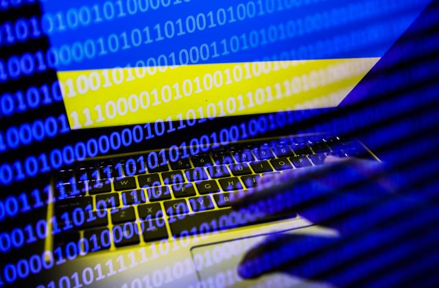 Ukrainian flag displayed on a laptop screen and binary code code displayed on a screen are seen in this multiple exposure illustration photo taken in Krakow, Poland on February 16, 2022. (Photo illustration by Jakub Porzycki/NurPhoto via Getty Images)