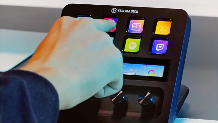 Lifestyle product image of a hand reaching up to press a button on the Elgato Stream Deck+ control panel.