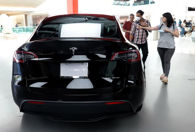 MIAMI, FLORIDA - OCTOBER 21: People look at a Tesla Model Y electric vehicle on a showroom floor at the Miami Design District on October 21, 2021 in Miami, Florida. Tesla reported $1.6 billion in profits for the months of July, August, and September, a record for them.  (Photo by Joe Raedle/Getty Images)