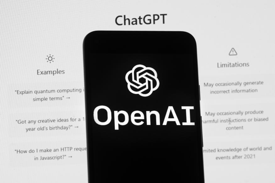 The OpenAI logo is seen on a mobile phone in front of a computer screen which displays the ChatGPT home Screen, Friday, March 17, 2023, in Boston. (AP Photo/Michael Dwyer)