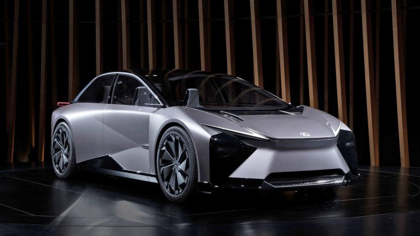 This futuristic grey, sporty Lexus EV concept has Robocop vibes and is seen on a black floor with slatted wood pillars behind it.