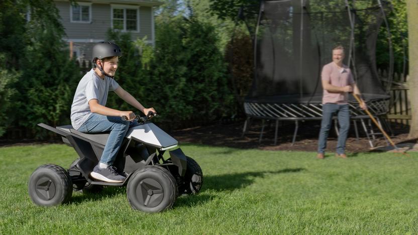 Lifestyle marketing photo of a boy riding an ATV that resembles the Tesla Cybertruck. A proud father beams from behind as he rakes leaves.