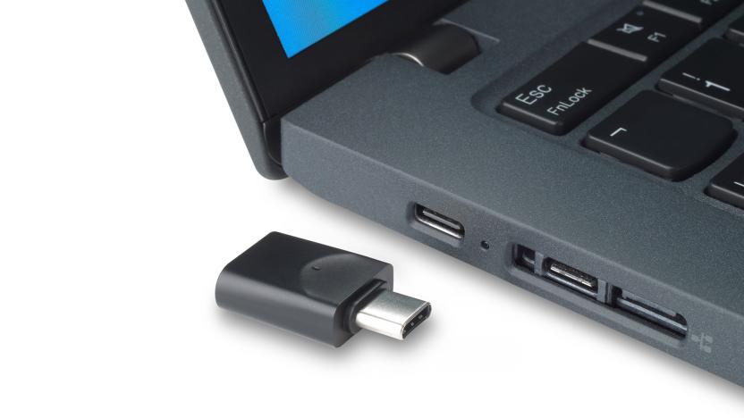 Marketing photo of a USB-C dongle sitting next to the side of a laptop