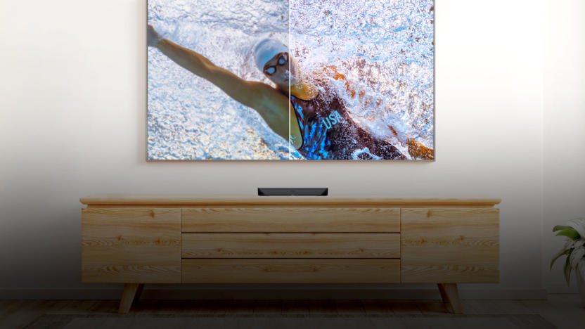 A TV showing a swimmer right above a console.