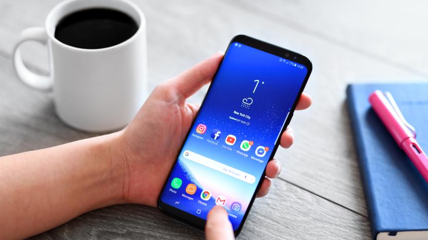 İstanbul, Turkey - March 7, 2017: Hand holding a smart phone on a wooden desk. The smart phone is an Samsung Galaxy S9 plus.  Samsung Galaxy is a touchscreen smart phone produced by Samsung Electronics.