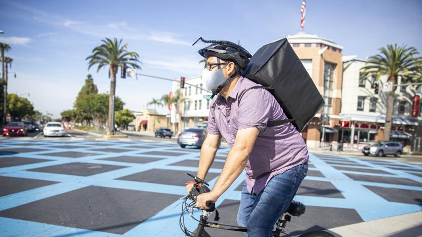 A young Hispanic man delivers food with his bicycle wearing a mask