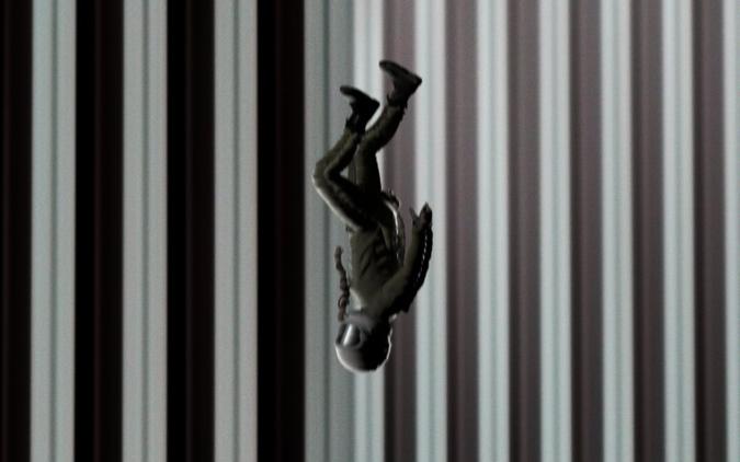 The artwork depicts an astronaut silhouetted against a series of alternating vertical lines. The piece clearly references “The Falling Man,” a photo that captures the moments before a 9/11 victim fell to their death.   