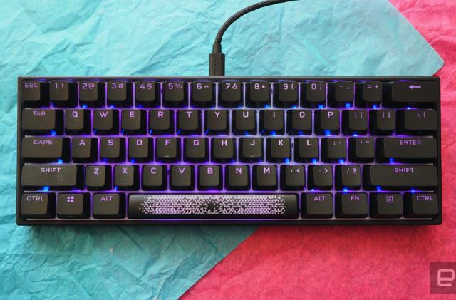 The Corsair K65 RGB Mini keyboard photographed on top of teal and red paper.