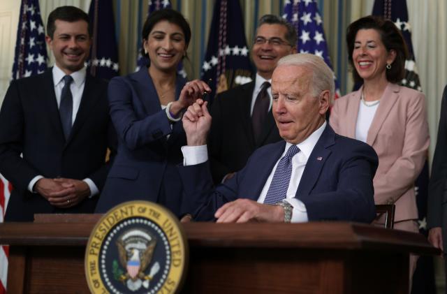WASHINGTON, DC - JULY 09:  U.S. President Joe Biden passes a signing pen to Chairperson of the Federal Trade Commission Lina Khan (2nd L) as (L-R) Secretary of Transportation Pete Buttigieg, Secretary of Health and Human Services Xavier Becerra, and Secretary of Commerce Gina Raimondo look on during an event at the State Dining Room of the White House July 9, 2021 in Washington, DC. President Biden signed an executive order on “promoting competition in the American economy.”  (Photo by Alex Wong/Getty Images)