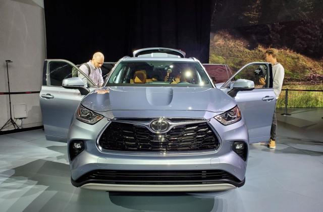 A front-view of a Toyota vehicle on display at the New York Auto Show, with doors open and people looking in.